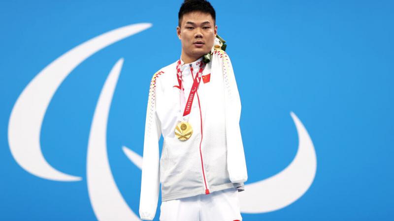 A man poses with a gold medal around his neck
