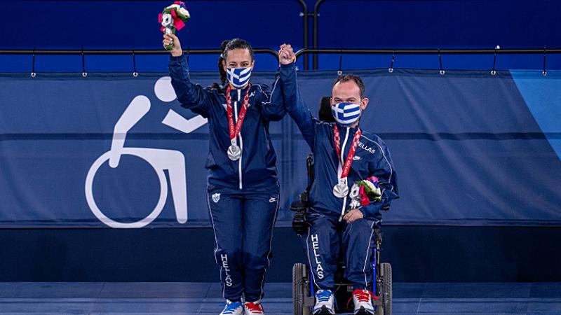 Grigorios Polychronidis with his wife and assistant hold up their hands to celebrate their silver medals 