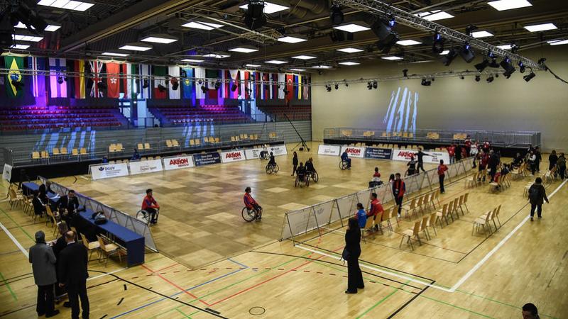 An indoor court with a group of Para dancers practicing observed by a group of people around the court