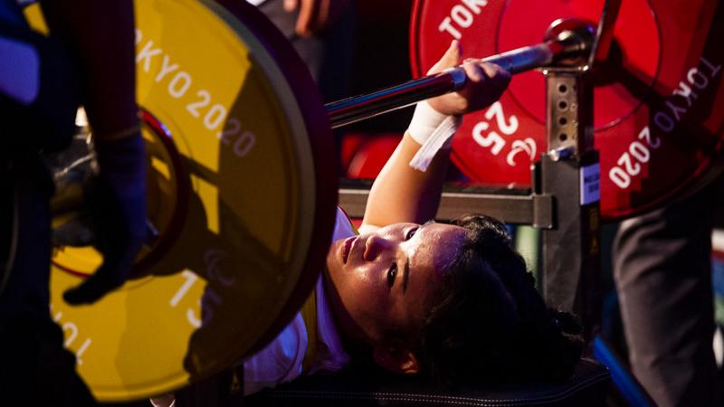 A woman on a bench press ready to lift a bar