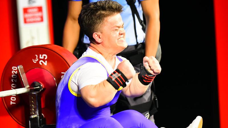 A short stature woman celebrating on a bench press