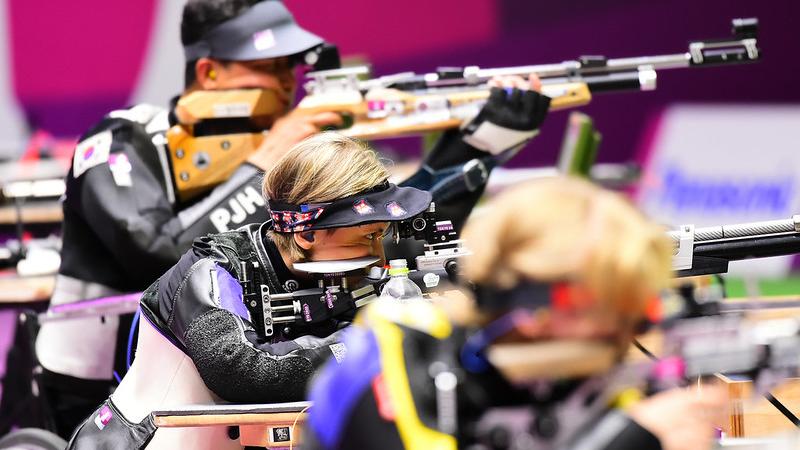 A woman competing in a shooting rifle competition between a male and a female shooter