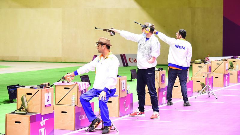 Three male pistol shooters competing in a shooting range