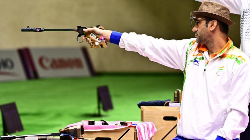 A man with a hat competing in a pistol shooting event in a shooting range