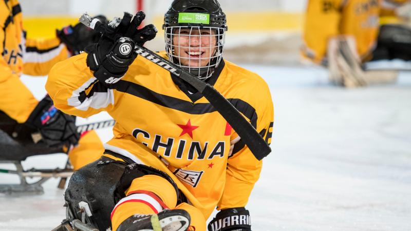 A Para ice hockey player celebrates scoring a goal with a smile on his face