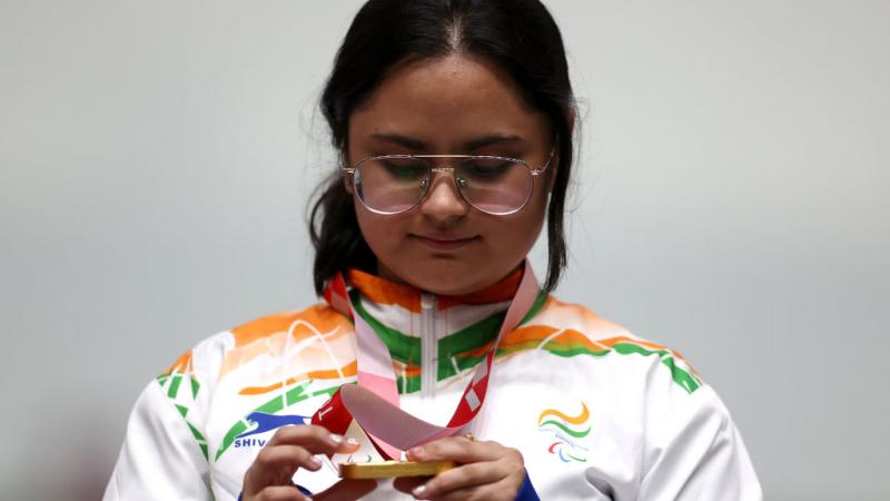A young woman looking at her gold medal