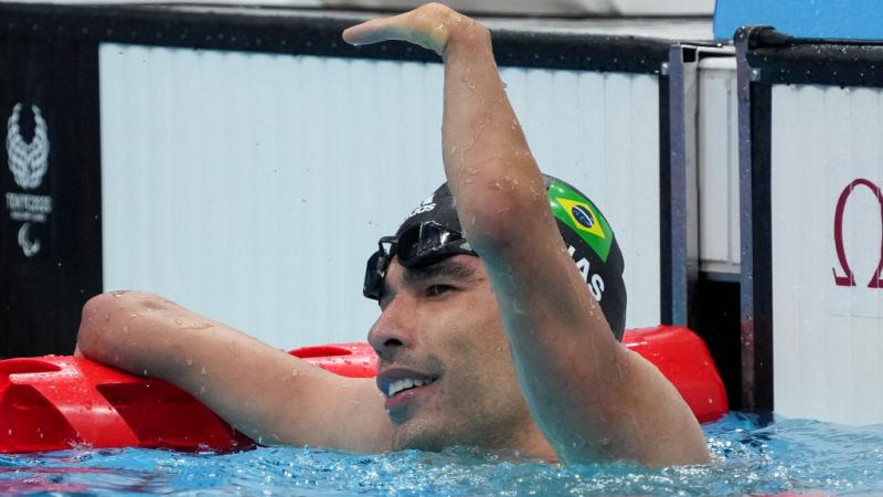 A handless swimmer waving from inside the pool