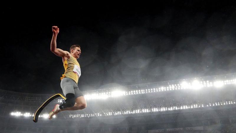 A man with a prosthetic leg jumping in a stadium