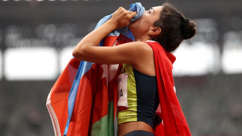 A female Para athletics athlete holding the flag of Azerbaijan