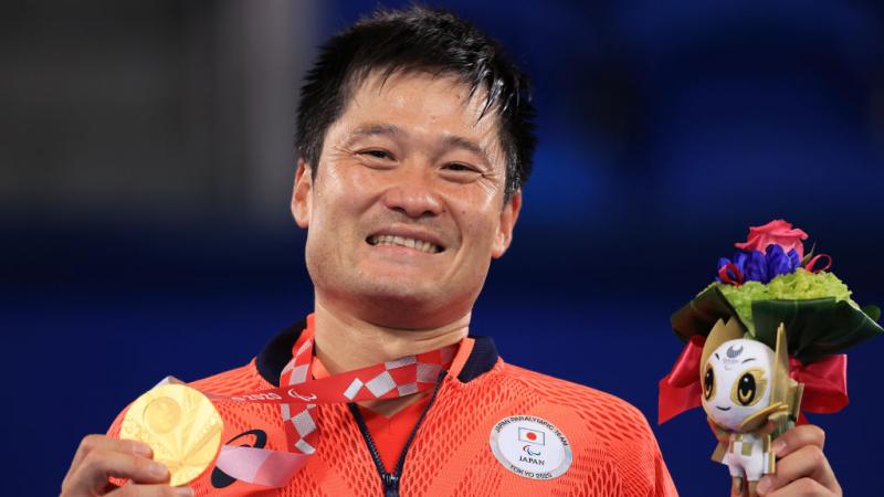 Shingo Kunieda holds his gold medal and mascot on podium