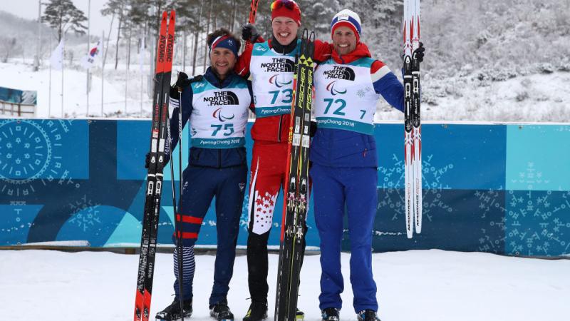 Three men standing on the snow with their skies 