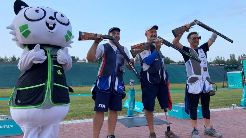 Three men standing with their shotguns near a person dressed as a mascot cat in a shooting range