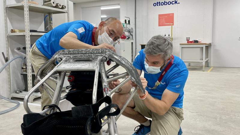 Two men wearing Ottobock shirts fixing a wheelchair