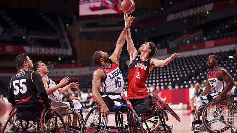 Two male wheelchair basketball athletes battle for rebound