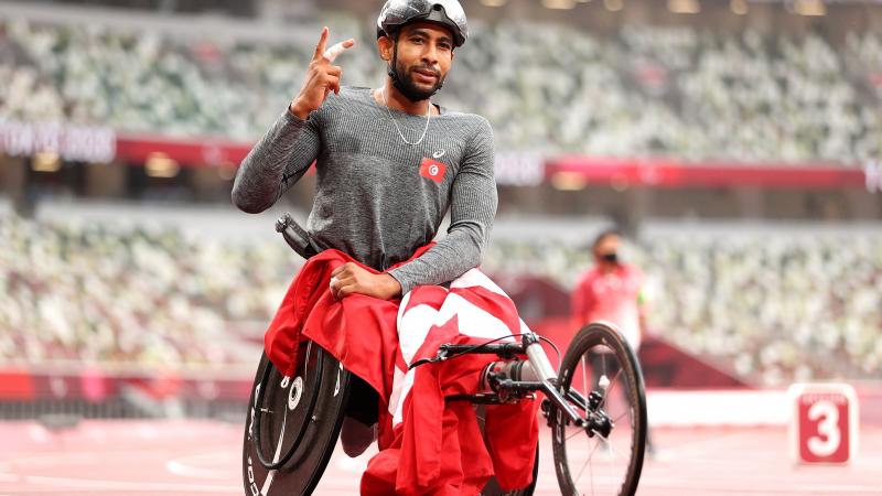 Wheelchair racer Walid Ktila celebrates with the Tunisian flag after winning the 800m 