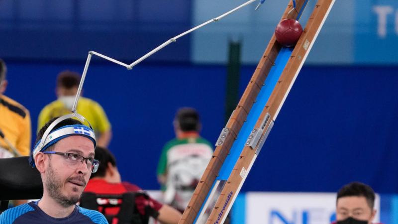 Boccia male athlete uses pointer to push ball