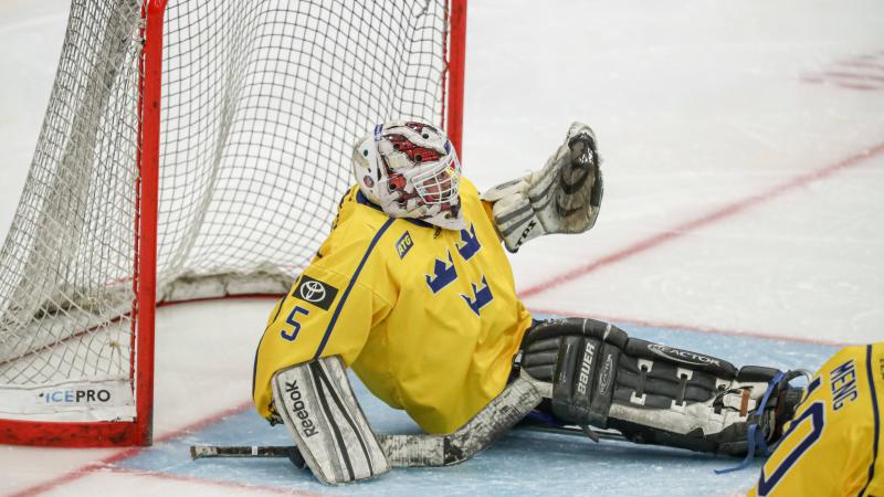 A Para ice hockey goalie holding a puck in his glove