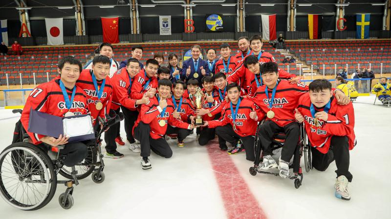 Para ice hockey players smiling and posing for a photo with the trophy and medals