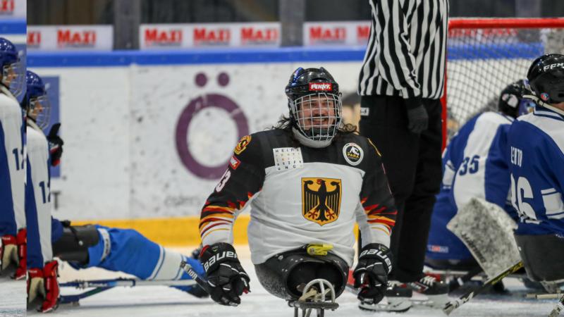 A man on a sled holding two sticks and smiling