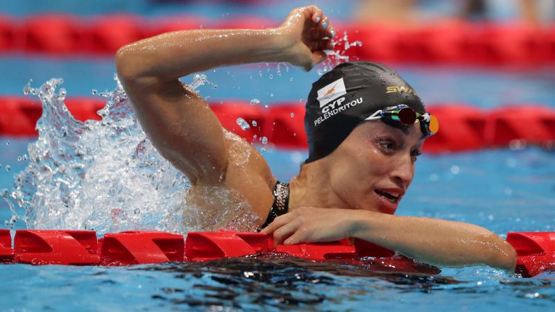 A woman celebrates in the pool with the right arm held high