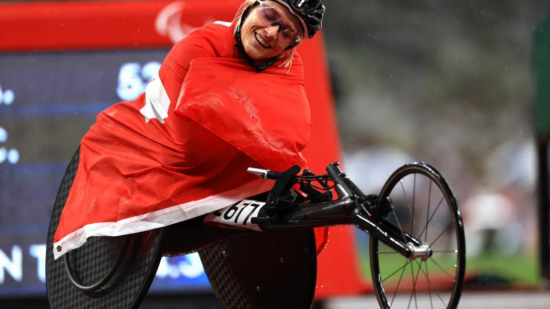 A woman sitting in a wheelchair wrapped around with the Swiss flag