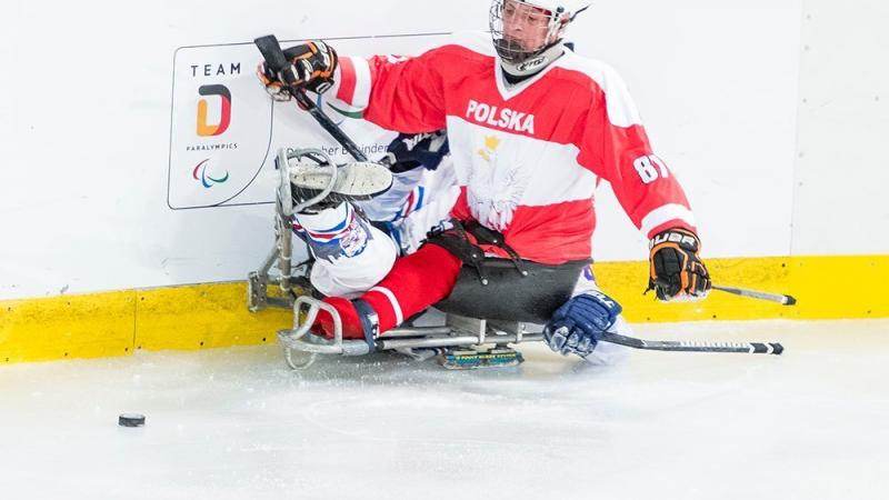 Para ice hockey player pushing another player to the fence