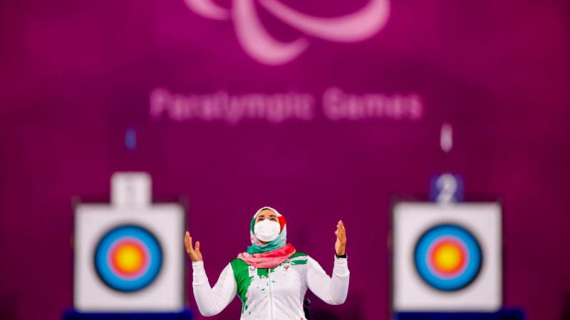 Iranian woman with mask puts hands in air and looks to sky