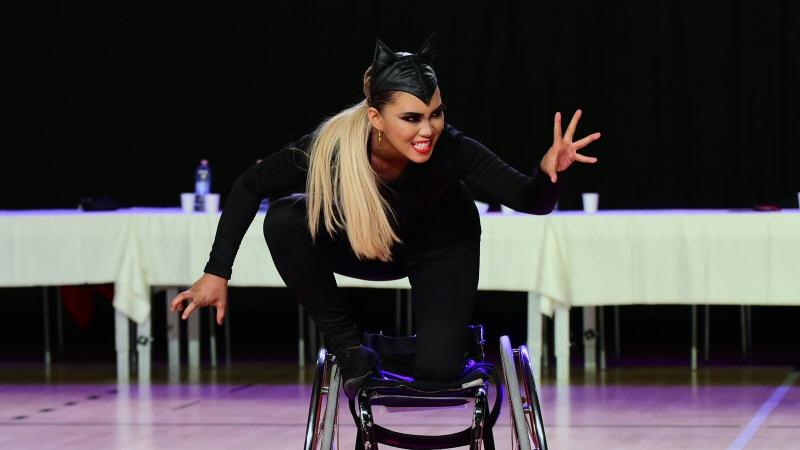 A woman dressed up in a cat performs in a wheelchair during a Para dance sport competition