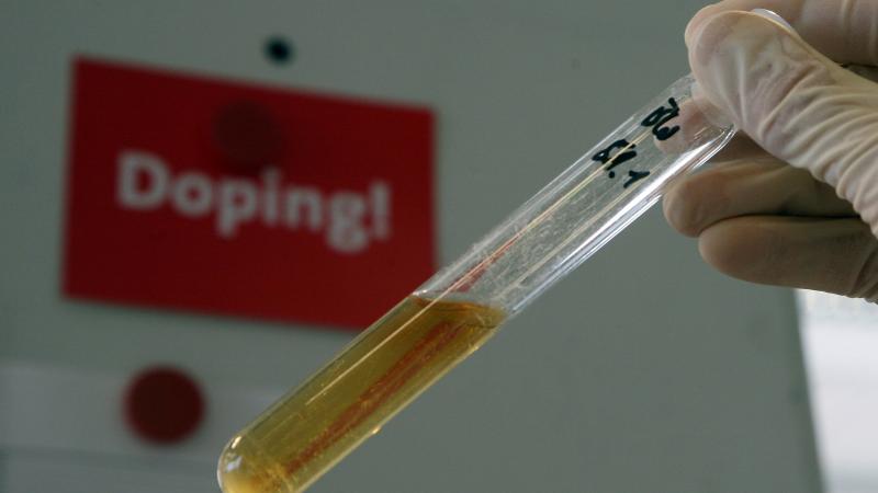 A test tube with a urine sample with a sign that says; "Doping!," behind it