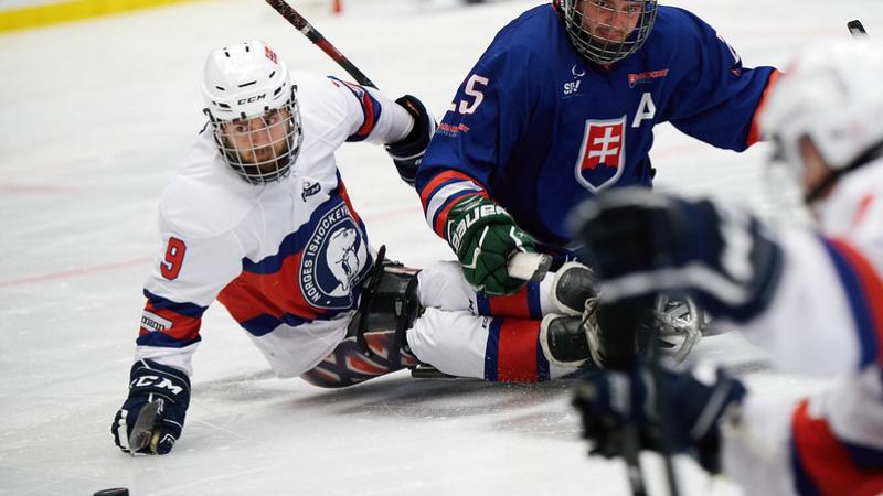 Two male Para ice hockey players chasing the puck 