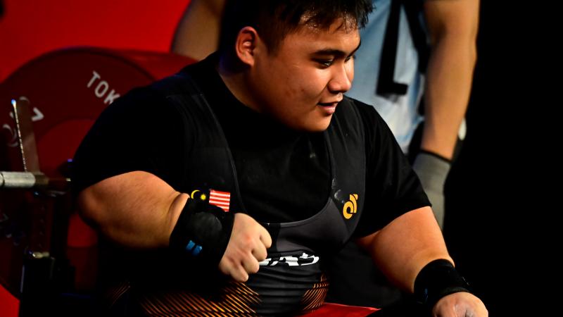 A man sitting on the bench after lifting the bar.