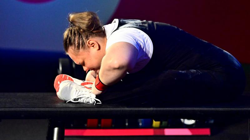 A female athlete stretching on the bench before her attempt.