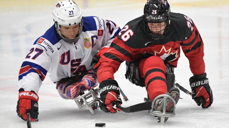 Two Para ice hockey players fighting to get the puck