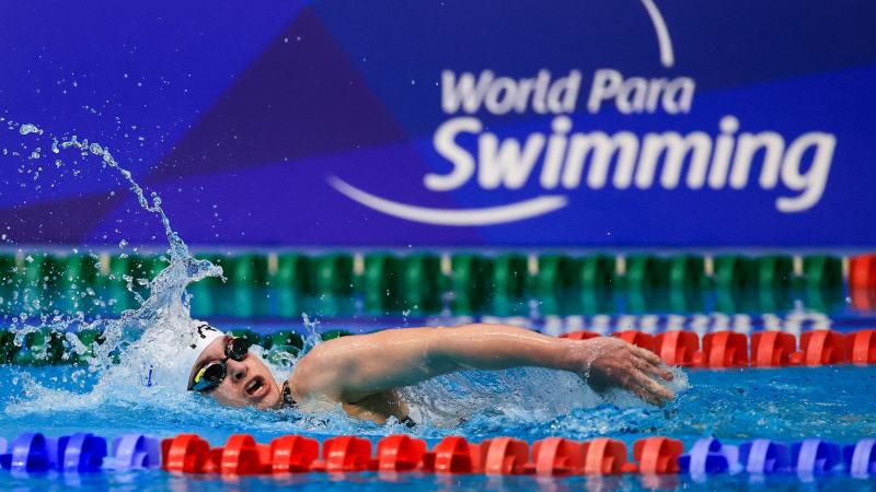 A female swimming in a pool with the logo of World Para Swimming on the background