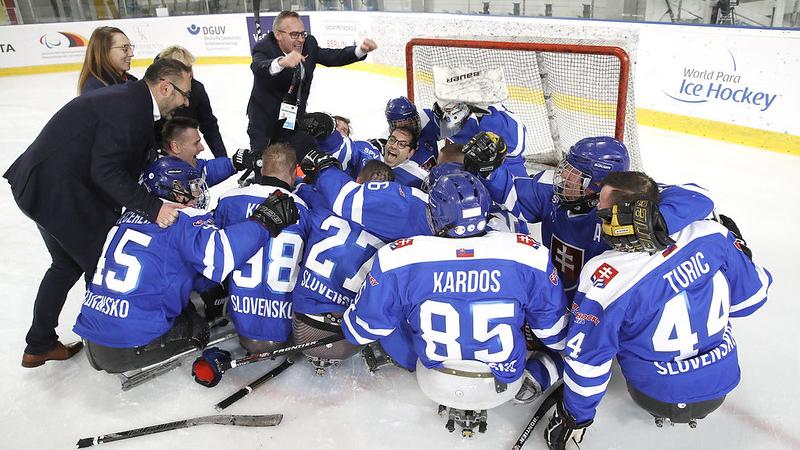 A group of Slovakian Para ice hockey players celebrating on an ice rink with four standing people