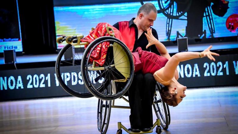 A male wheelchair dancer holding a female wheelchair dancer on his lap