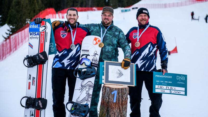 Three male snowboarders in a medal ceremony on the snow