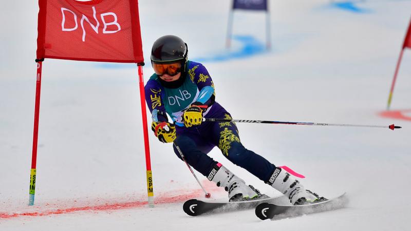 A female Para alpine skier crossing a red gate on a parallel event 
