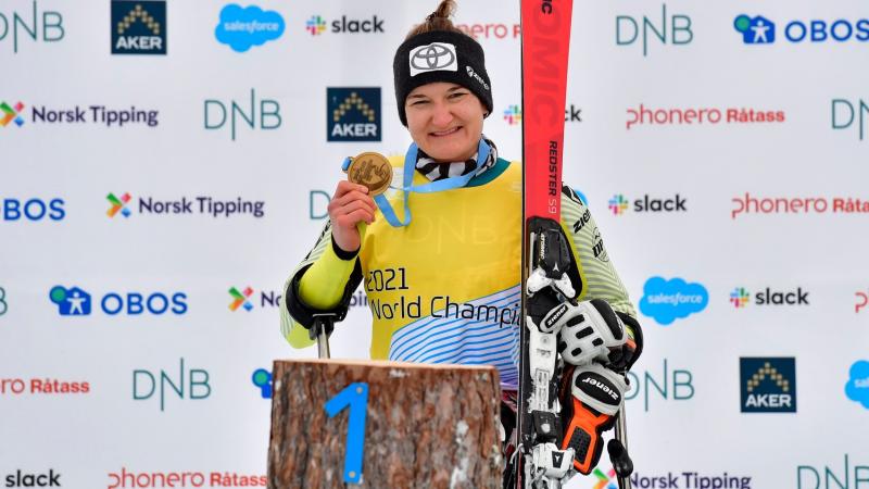 A female skier showing her gold medal in a medal ceremony