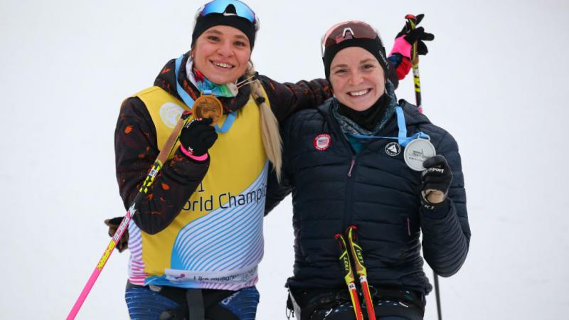 Two smiley women showing their medals in a snow sport competition