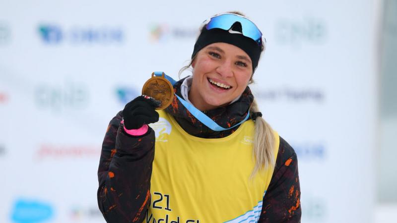 A woman smiling and showing her gold medal 