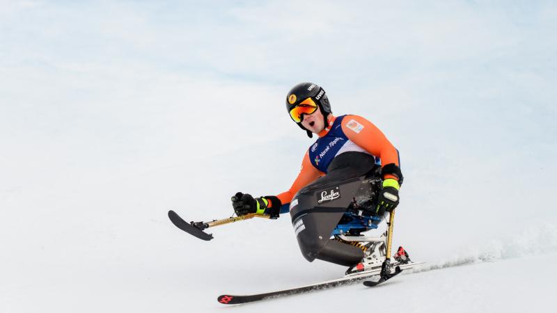 A sit-skier making a turn in a Para alpine skiing competition