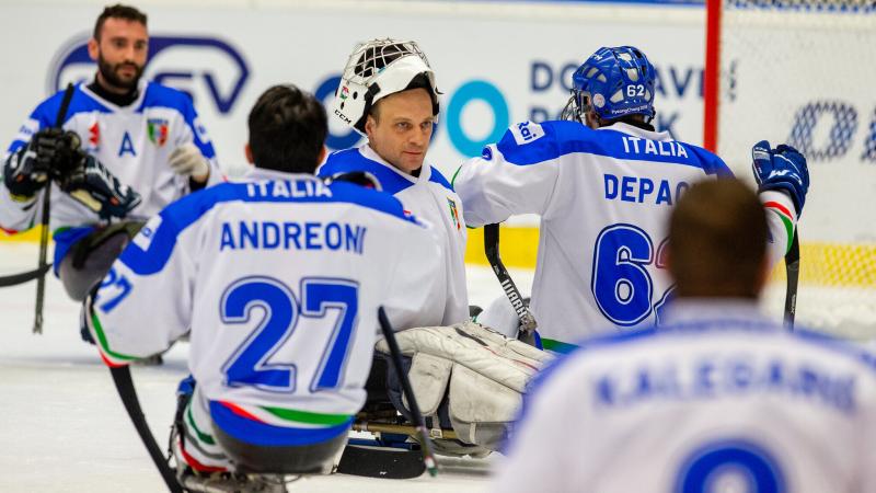 A goalie congratulated by his teammates on the ice