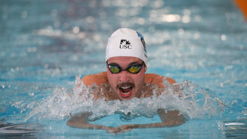 A man with a moustache swimming in the pool.