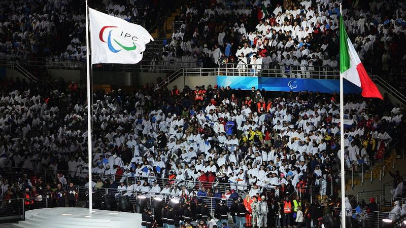 The International Paralympic Committee flag and the Italian national flag fly side by side during the Opening Ceremony of the Turin 2006 Paralympic Winter Games. 