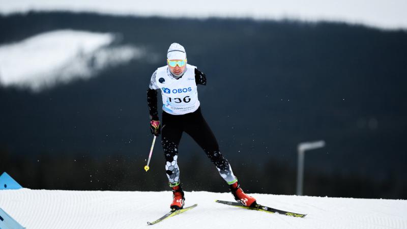 A man with two ski's and one stick in his right hand goes downhill on the snow circuit