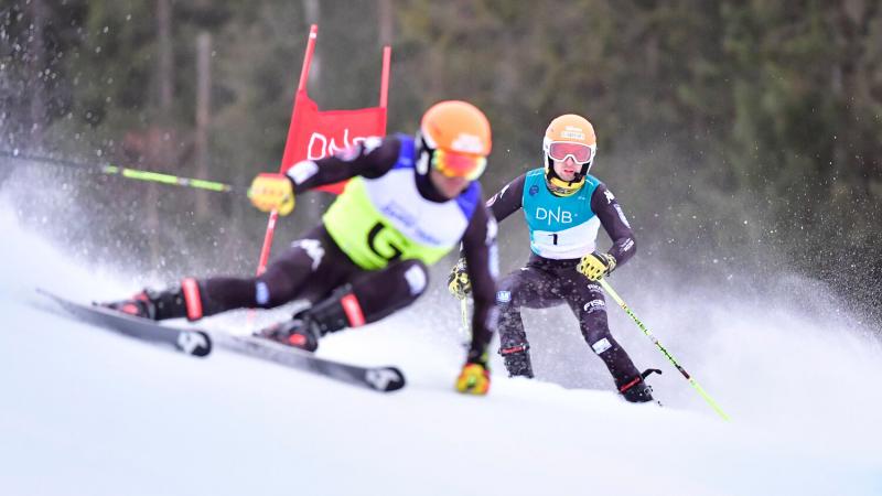 A man skiing with a microphone behind his guide.