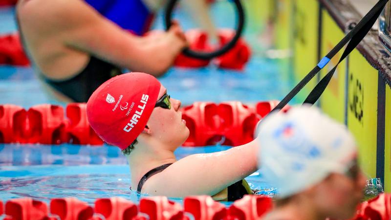 A female swimmer in the pool, hanging onto a rope with both hands before the race start.