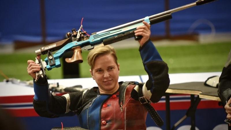 A female shooter raising her competition rifle above her head