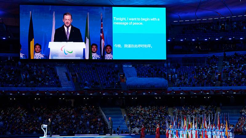 Andrew Parsons is pictured on a large screen at the Opening Ceremony of Beijing 2022 alongside a sentence of his speech which reads: 'tonight I want to begin with a message of peace'